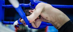 Exhausted boxer leaning against the ropes in a boxing ring