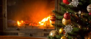 Decorated Christmas tree beside a glowing fireplace