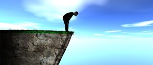 Man looking over the edge of a steep cliff