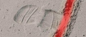 Footprints crossing a red line drawn in the sand