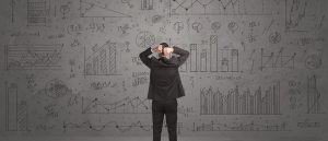 Businessman reviewing charts, graphs, and data calculations on a wall