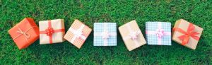 A row of colorful gift boxes wrapped in various designs placed on green grass.