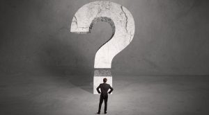Businessman standing in front of a large question mark, representing a negotiation dilemma