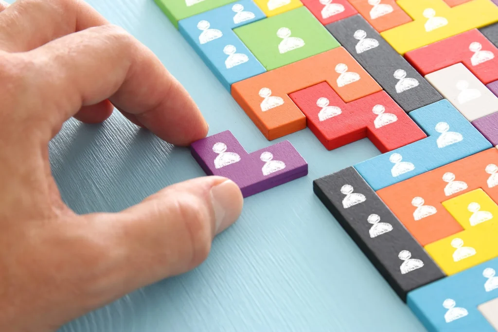 Hand placing a people-shaped puzzle piece into a team