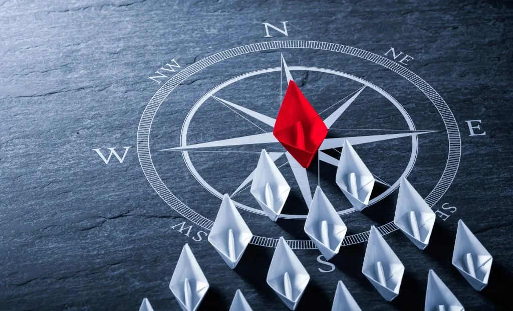 Red paper arrow leading a group across a compass