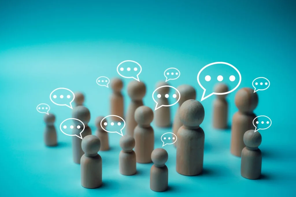 Wooden figures with speech bubbles representing communication and discussion