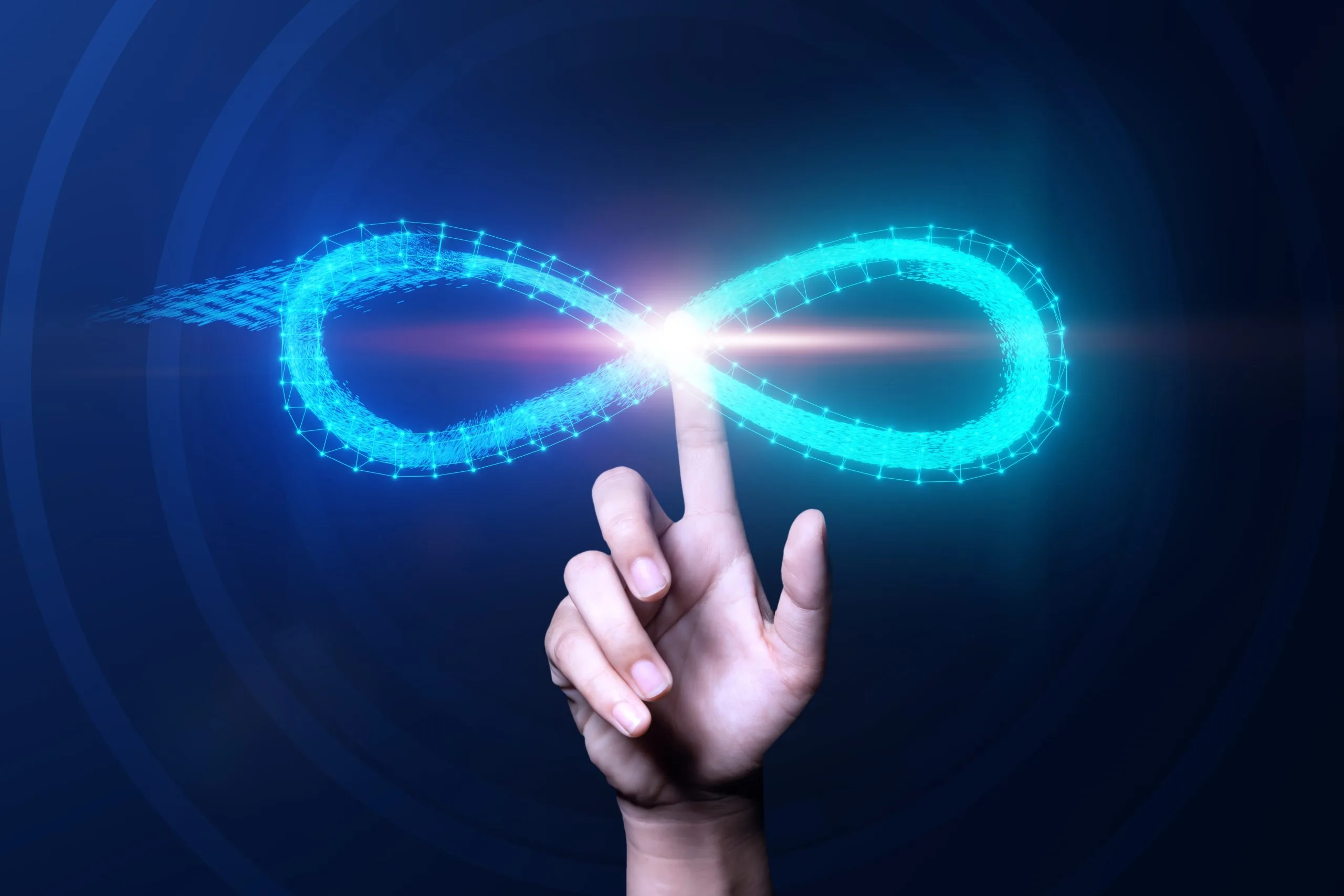 A hand with an outstretched index finger touches the center of a glowing blue infinity symbol, set against a dark background. Light radiates from where the finger meets the symbol.
