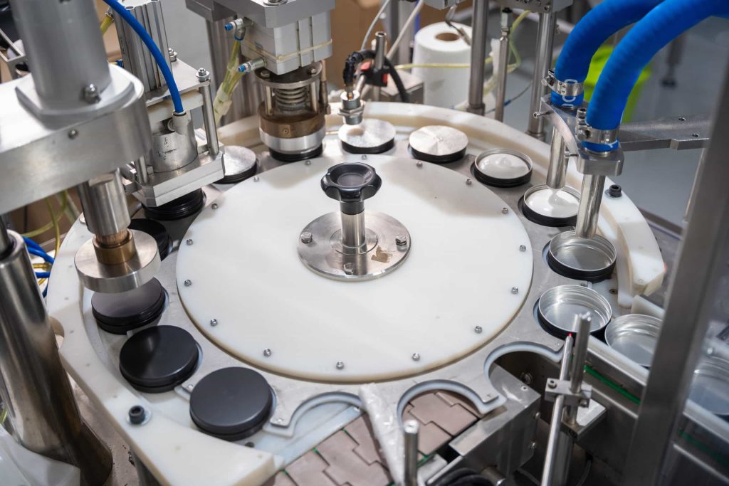 Automated industrial machine filling and sealing containers on a production line