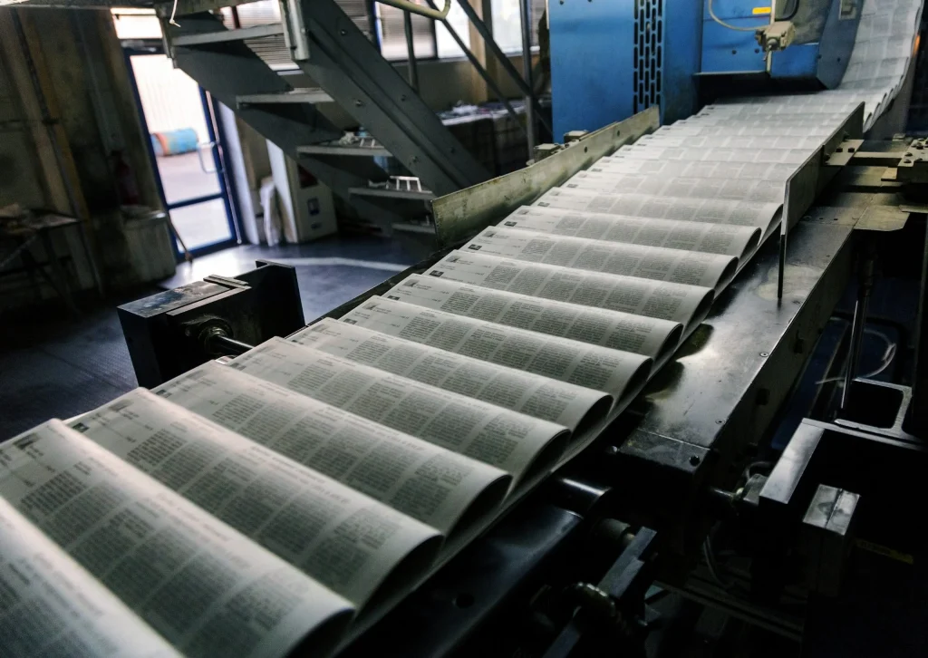 Newspapers moving through a printing press